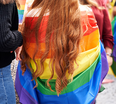 A pride flag wrapped around a young person
