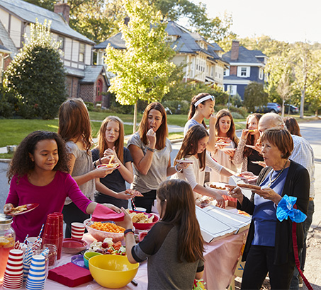 A neighbourhood street party with children and adults around a table
