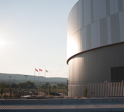 A round building with the sun shining and flags flying in the background