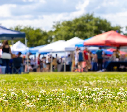 Residents mingling around outdoor tents on a summer day