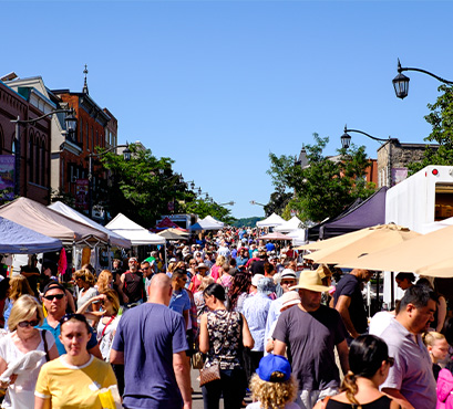 A crowd of people walking through a downtown street festival