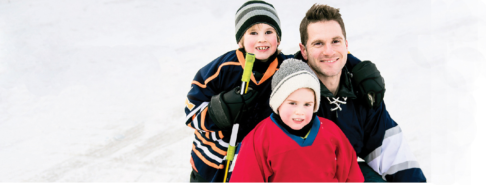 A man and two boys on the ice for Family Day
