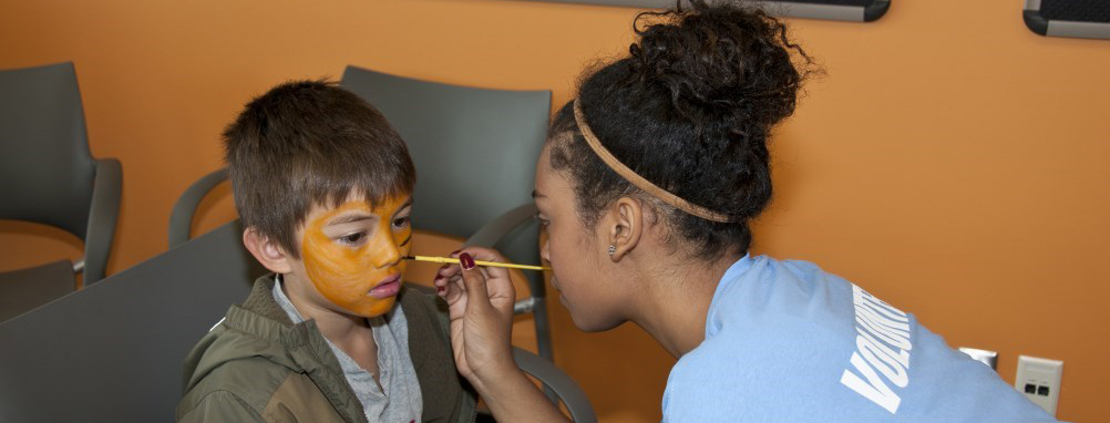 Volunteer facepainting a child