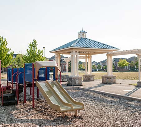 A playground set with a slide and gazebo behind it