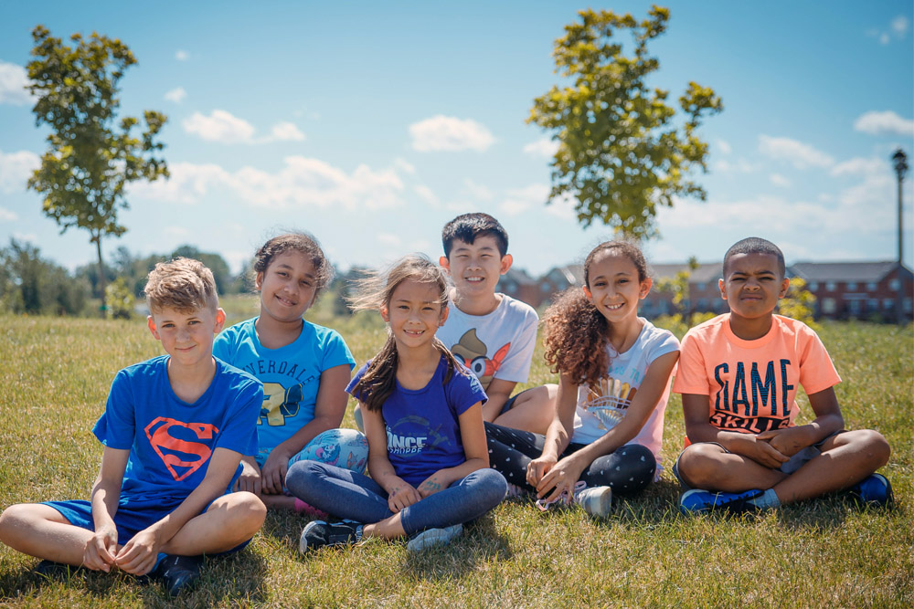 Four children sitting on a hill at summer camp