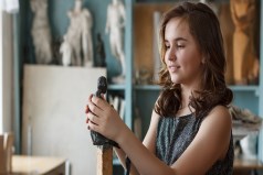 Young girl sculpting with with finished sculptures in the background