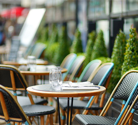 A line of patio tables with glasses on them