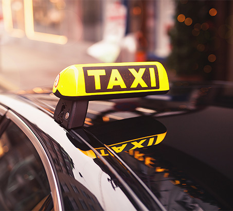 A taxi sign on top of a black vehicle
