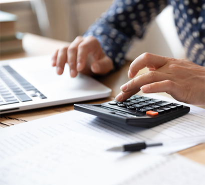 A person working at a laptop with a calculator