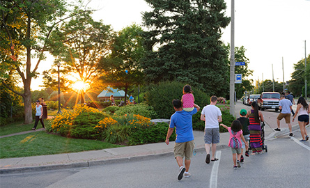 A family crossing the street while the sun sets