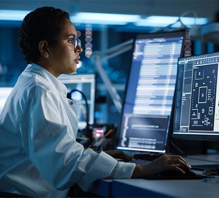 A woman sitting at a computer working at a program