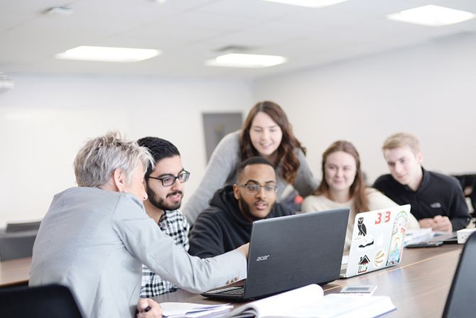 People sitting around a laptop communicating