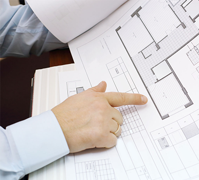 A hand pointing to a floor plan on paper