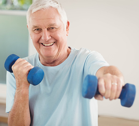 An older adult smiling holding hand weights