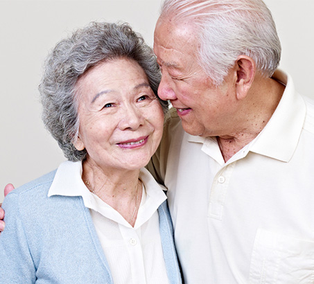 Two older adults leaning into each other and smiling