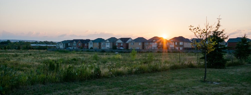 the sun setting over houses in  of a Milton neighbourhood.