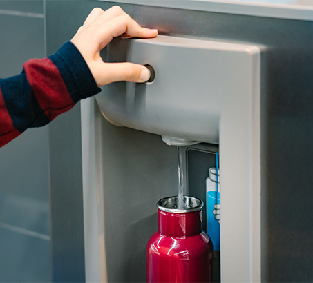 A reusable water bottle being filled at a water station