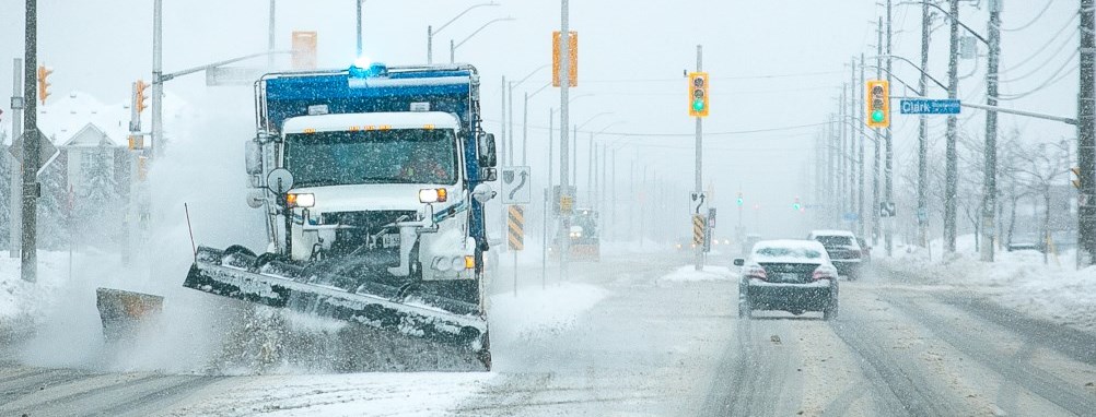 snow plow on a Milton street in a snowstorm