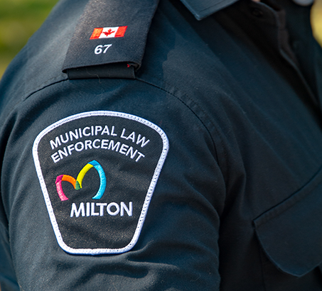 A Municipal Law Enforcement Milton badge on the arm of a by-law officer