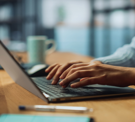 A pair of hands typing on a laptop