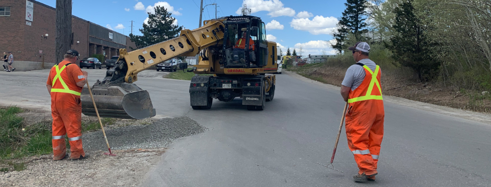 Town staff working on a road with a back hoe