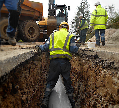 A road construction worker standing in a crevice over a pipe