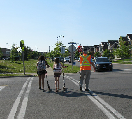 A crossing guard helping two children cross the street