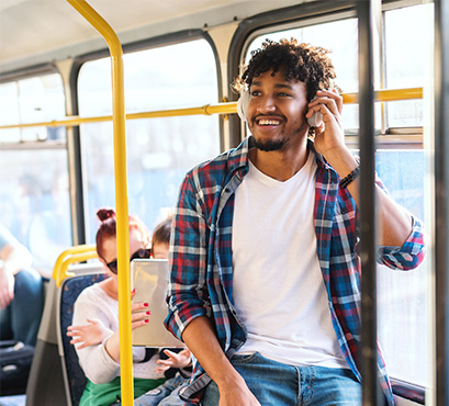 A man on a bus on the phone smiling