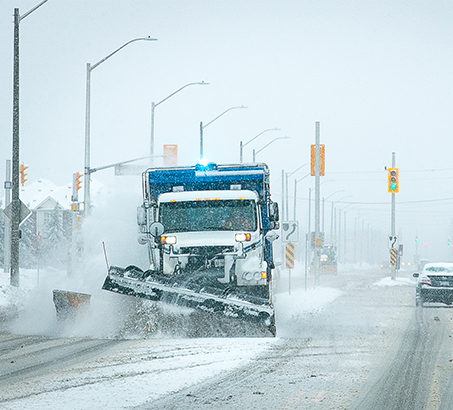 Small tractor salting an icy sidewalk