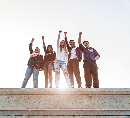 A group of youth standing on a cement wall with the sun shining
