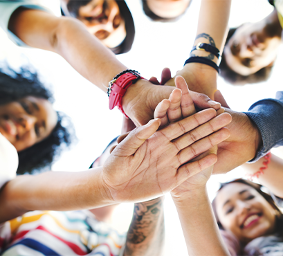 Teens in a circle with their hands in the middle