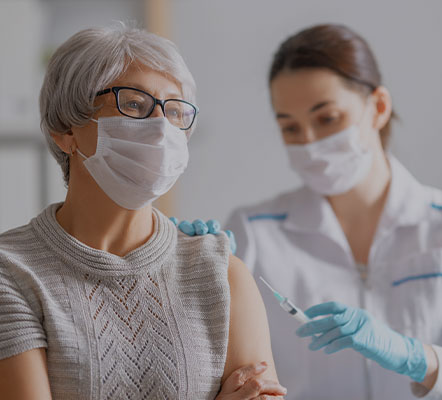 Medical professional administering vaccine to older adult woman
