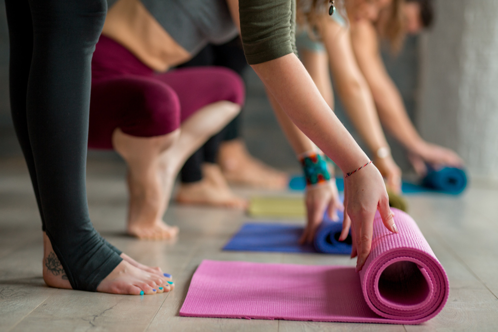 person rolling out yoga mat