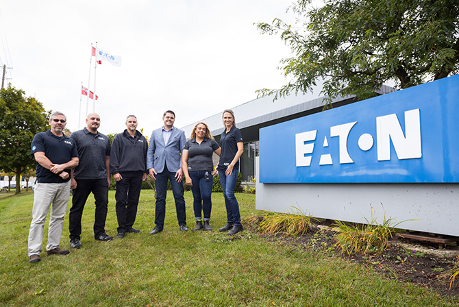 Employees standing in front of Eaton sign