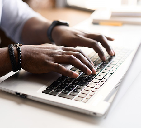 Hands typing on a laptop