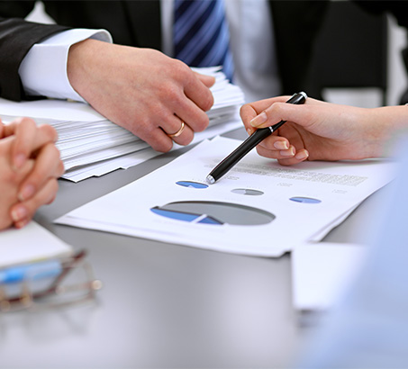 Hand holding a pen pointing at graphs on a piece of paper