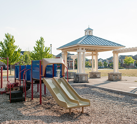 A playground with bright green trees in the background