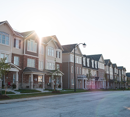 A row of houses on a street with the sun shining down