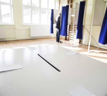 A ballot box with windows and drapes in the background
