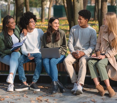 A group of young adults sitting on a bench smiling